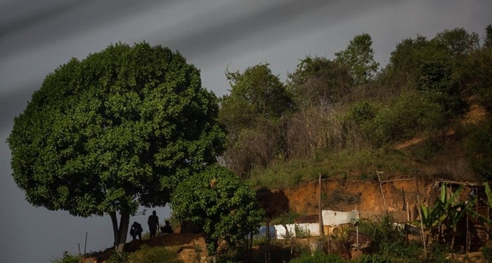 Un grupo de policías se esconden detrás de un árbol en una montaña durante un enfrentamiento con criminales en La Vega, el 07 de junio de 2021, en Caracas (Venezuela).