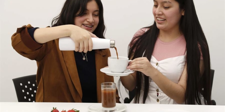 Las estudiantes Alexa Castañeda (d) y Esther Rivera de la Universidad de Ciencias y Artes de América Latina (UCAL) presentan una bebida preparada a base de grillos, el 29 de junio de 2021, en Lima (Perú).