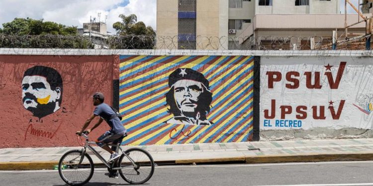 n hombre pasa en su bicicleta frente a un mural con la imagen del presidente de Venezuela, Nicolás Maduro (i) y de Ernesto "Che" Guevara (c) , el 26 de julio de 2021, en Caracas (Venezuela).  Ronald Peña / EFE