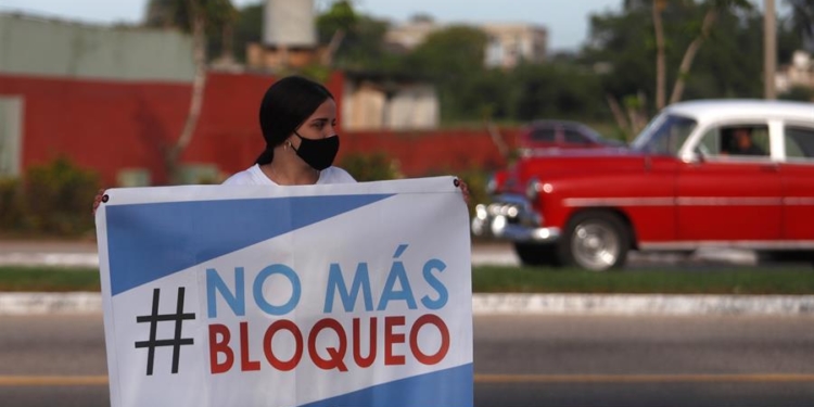 Fotografía del 20 de junio que muestra a una mujer que sostiene un cartel, durante la regata parte de una campaña contra el bloqueo de Estados Unidos a la isla, en la bahía de Matanzas (Cuba).