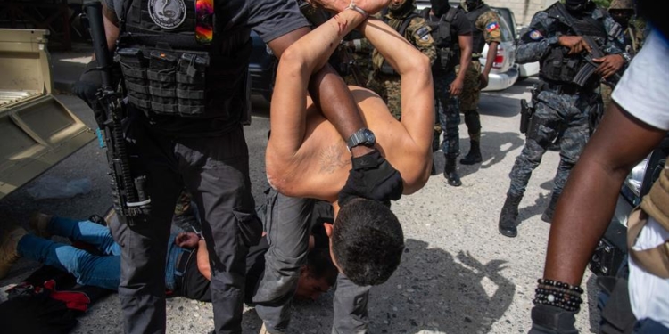 Policías custodian a un grupo de sospechosos del asesinato del presidente haitiano, Jovenel Moise.