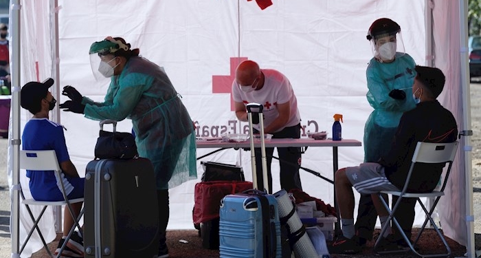 Varios trabajadores de Cruz Roja realizan una prueba PCR a un joven este jueves en Valladolid, momentos antes de subir al autobús que le lleva a un campamento de verano.