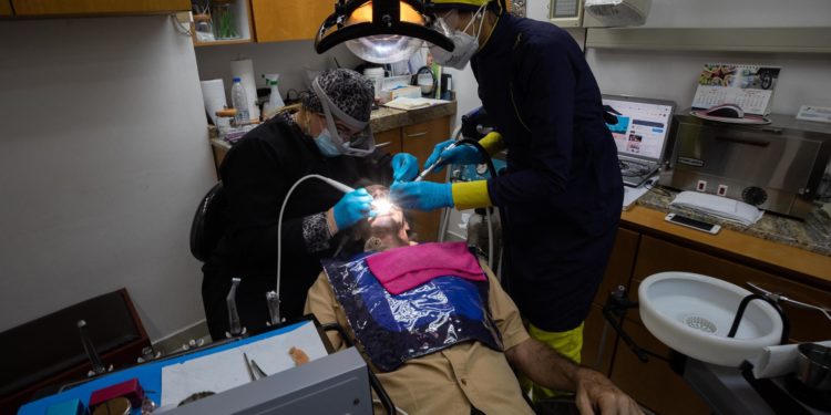 Dentistas voluntarias asisten a un hombre en un consultorio privado, el 17 de agosto de 2021, en Caracas (Venezuela). Alimentos o medicinas. Esa es la disyuntiva a la que se enfrentan miles de adultos mayores en Venezuela, ya que la pensión que perciben, que no supera los 10 dólares mensuales, no alcanza para cubrir ambas necesidades. Esta situación ha convertido a los ancianos en foco de atención de quienes reparten ayuda humanitaria / Rayner Peña / EFE.