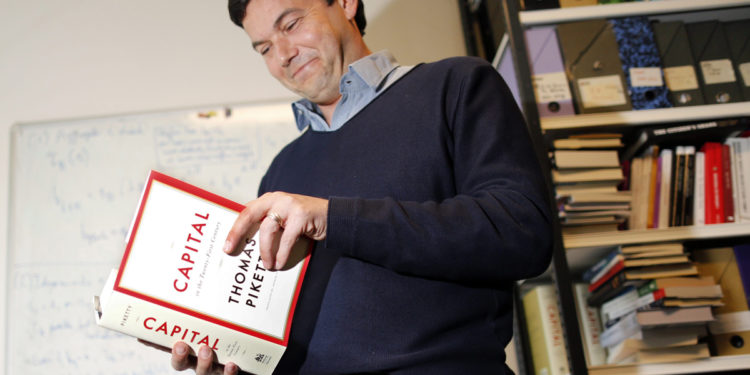 French economist and academic Thomas Piketty, poses in his book-lined office at the French School for Advanced Studies in the Social Sciences (EHESS), in Paris May 12, 2014. The 43-year-old Piketty's book "Capital in the Twenty-First Century" has attracted praise and invective alike on its way to the top of the Amazon.com books best-seller list. Picture taken May 12, 2014.  REUTERS/Charles Platiau (FRANCE - Tags: POLITICS SOCIETY BUSINESS EDUCATION)CODE: X00217