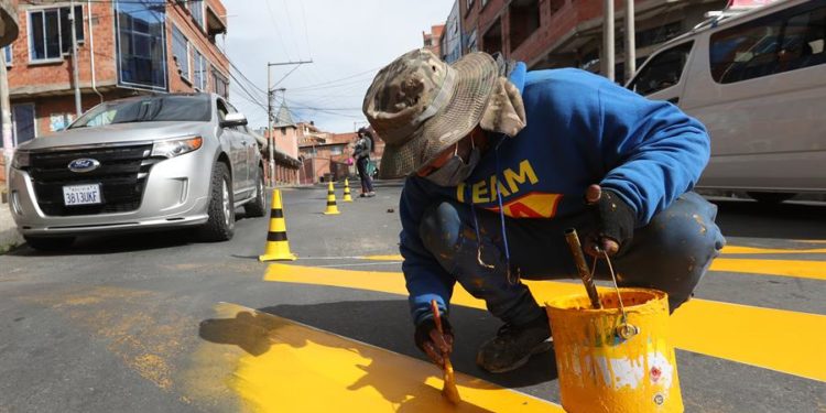 El venezolano Jesús Hernández pinta reductores de velocidad, el 31 de marzo de 2022 en una avenida de La Paz, Bolivia / Martín Alipaz / EFE.
