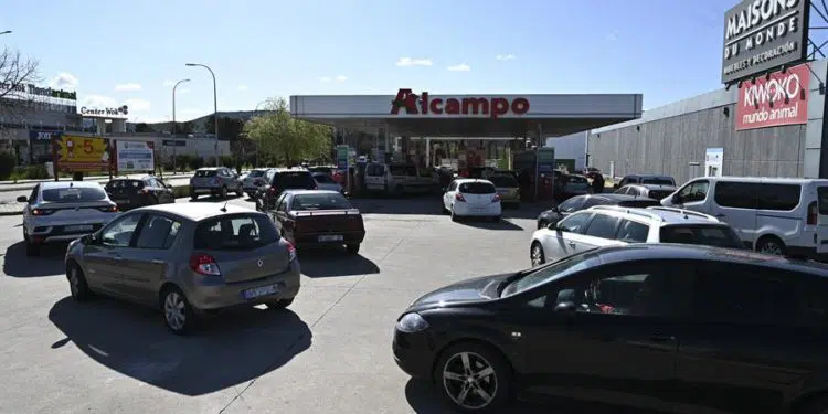 Coches hacen cola ante una estación de servicio en la localidad madrileña de Alcalá de Henares, este viernes, cuando entra el vigor la rebaja mínima obligatoria de 20 céntimos por litro. EFE/ Fernando Villar