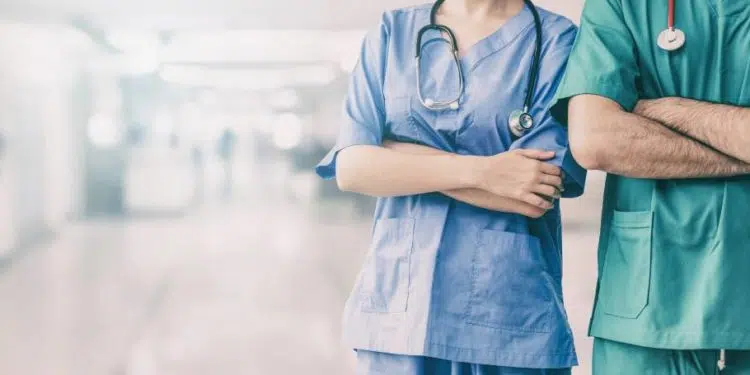 Two hospital staffs - surgeon, doctor or nurse standing with arms crossed in the hospital. Medical healthcare and doctor service. (Two hospital staffs - surgeon, doctor or nurse standing with arms crossed in the hospital. Medical healthcare and doctor