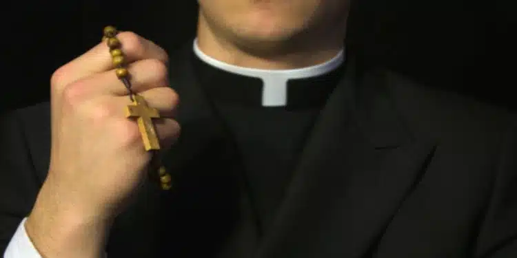 Young Priest praying with rosery in his hand