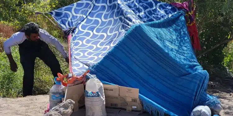 Un migrante organiza una carpa hecha por cobijas a orillas del Río Bravo, el 1 de julio de 2024 en Ciudad Juárez (México). Albergues de la frontera norte de México temen una nueva oleada migratoria al cumplirse dos semanas del anuncio del presidente de Estados Unidos, Joe Biden, para regularizar a cientos de miles de indocumentados casados con estadounidenses y a sus hijos. EFE/ Luis Torres